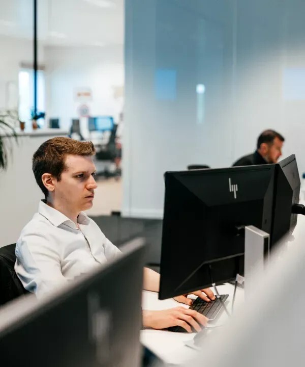 Collega van Becosoft aan een bureau met twee schermen op kantoor