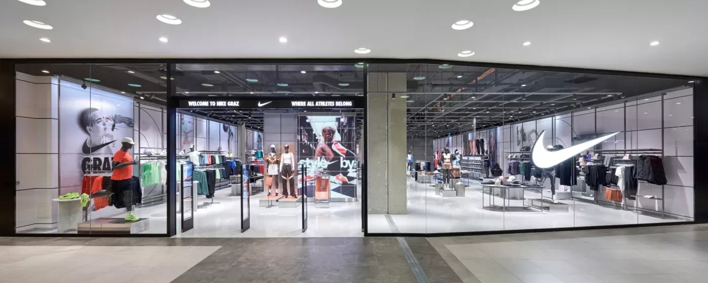 Sportswear store seen through its glass shopfront, with mannequins and clothing rails inside
