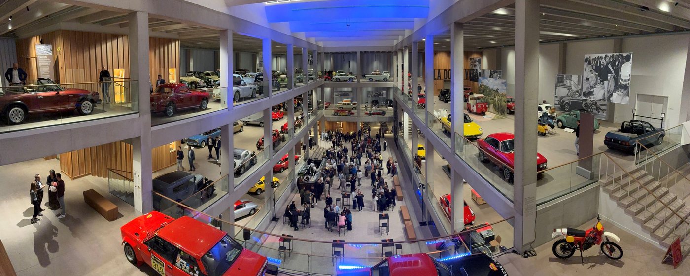 Bezoekers in een automuseum met klassieke wagens op meerdere verdiepingen